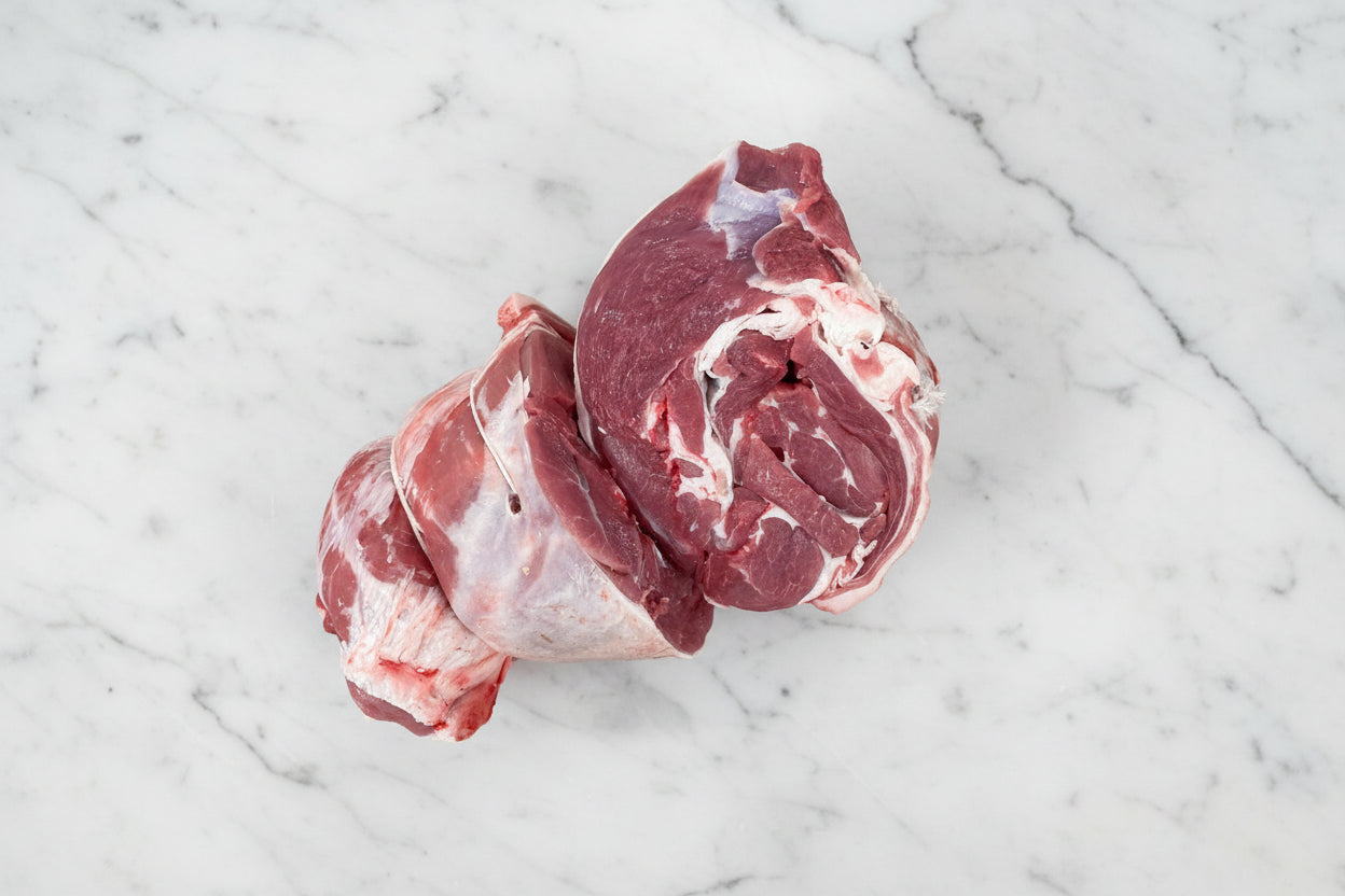 A boned and rolled lamb shoulder on a butcher block.